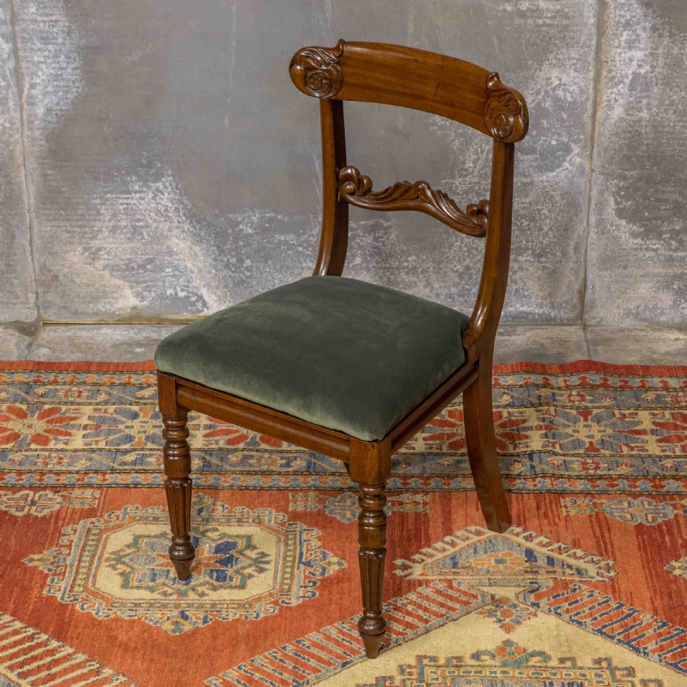 A set of six William IV mahogany dining chairs featuring carved top rails, turned front legs, and green velvet upholstered seats. View VII