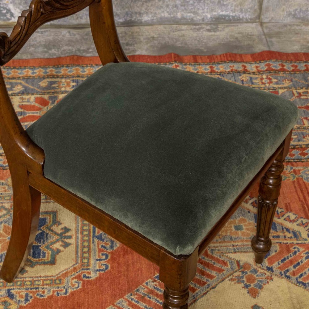 A set of six William IV mahogany dining chairs featuring carved top rails, turned front legs, and green velvet upholstered seats. View X