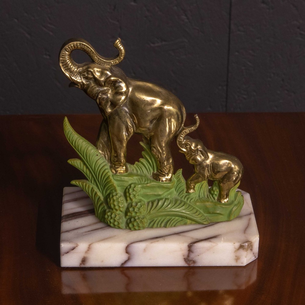 A pair of Art Deco brass elephant bookends with green painted foliage bases mounted on white veined marble plinths holding two books. View II