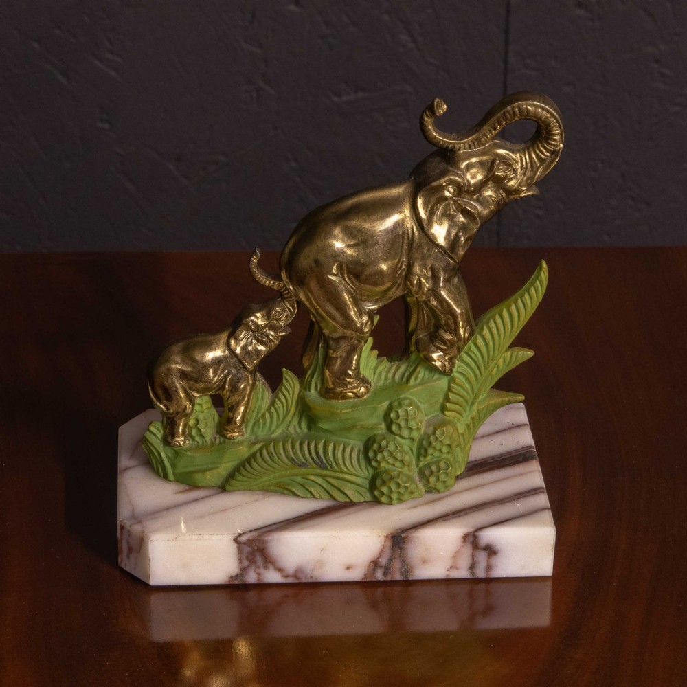 A pair of Art Deco brass elephant bookends with green painted foliage bases mounted on white veined marble plinths holding two books. View III