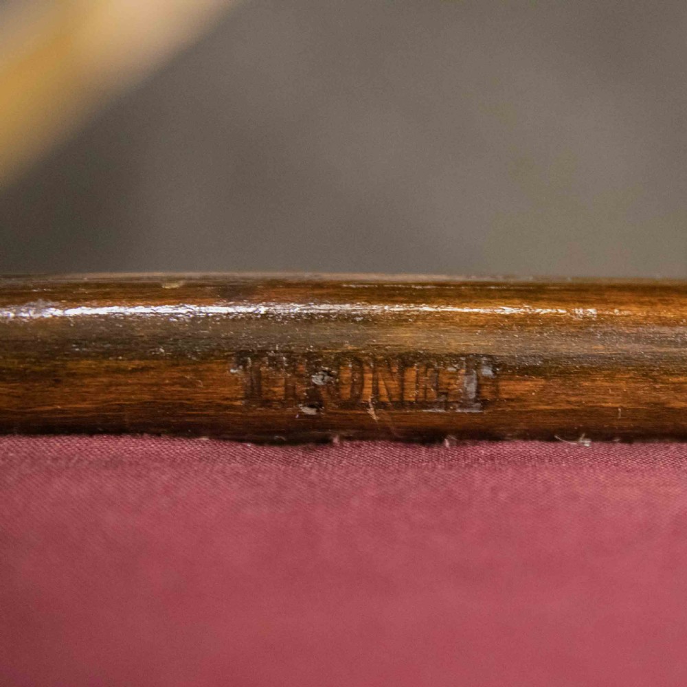 An antique Thonet steam-bent wood rocking chair featuring dark brown leather upholstered seating and brass studding along the frame. View II