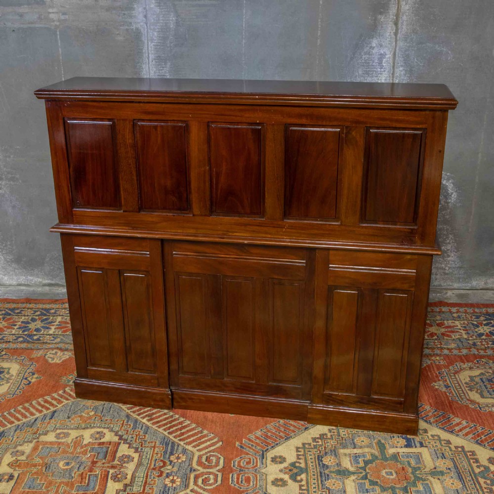 A mahogany roll top desk featuring a curved tambour shutter, internal pigeonhole compartments, a green leather inset writing surface, and twin pedestal drawers with brass drop handles. View XVII
