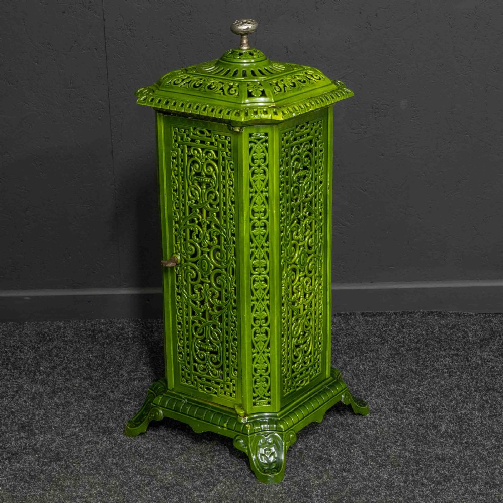 A tall rectangular green enamelled cast iron stove with elaborate openwork pierced filigree patterning and scrolled feet.