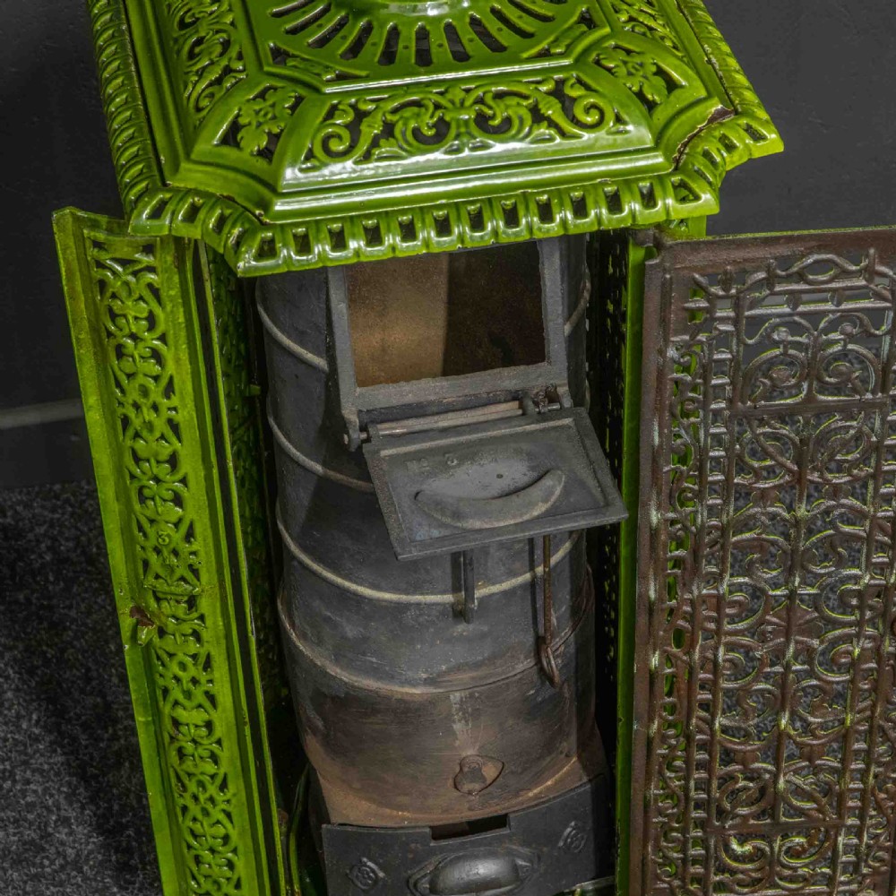A tall rectangular green enamelled cast iron stove with elaborate openwork pierced filigree patterning and scrolled feet. View IV