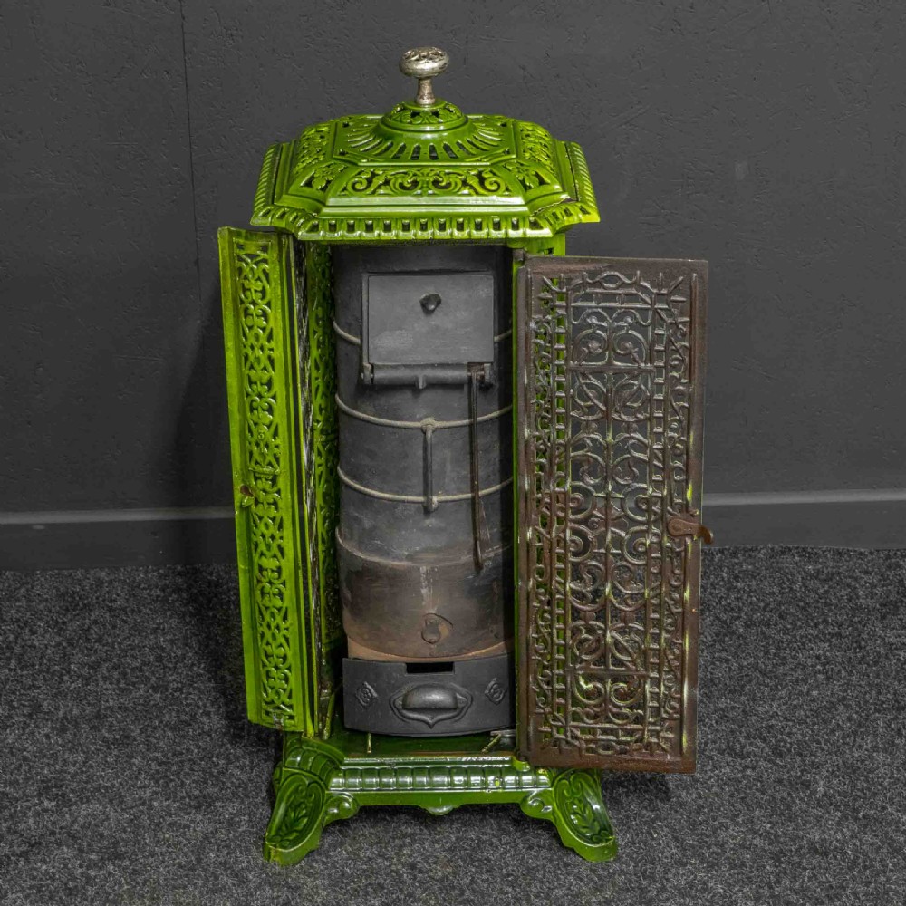 A tall rectangular green enamelled cast iron stove with elaborate openwork pierced filigree patterning and scrolled feet. View V