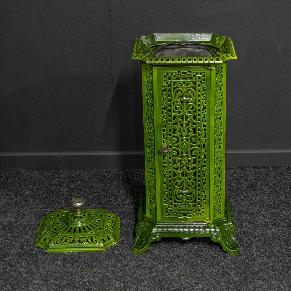 A tall rectangular green enamelled cast iron stove with elaborate openwork pierced filigree patterning and scrolled feet. View VI