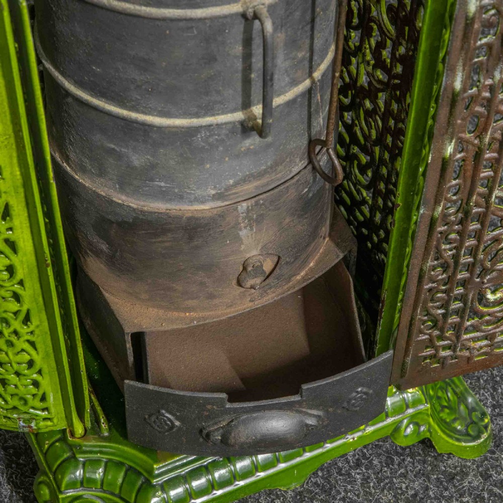 A tall rectangular green enamelled cast iron stove with elaborate openwork pierced filigree patterning and scrolled feet. View VIII