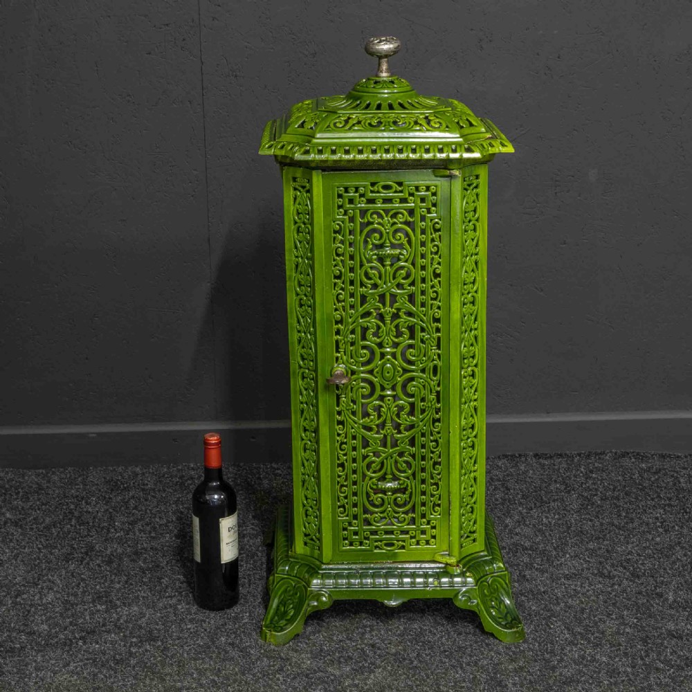 A tall rectangular green enamelled cast iron stove with elaborate openwork pierced filigree patterning and scrolled feet. View IX