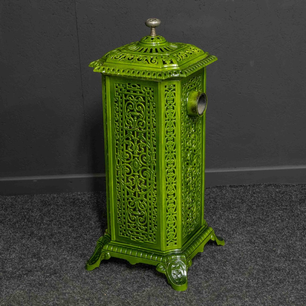 A tall rectangular green enamelled cast iron stove with elaborate openwork pierced filigree patterning and scrolled feet. View X