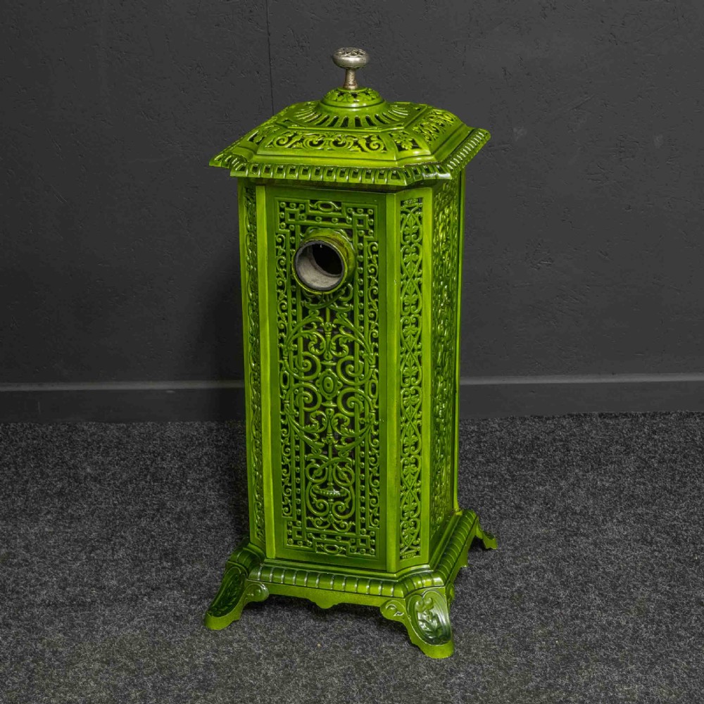 A tall rectangular green enamelled cast iron stove with elaborate openwork pierced filigree patterning and scrolled feet. View XI
