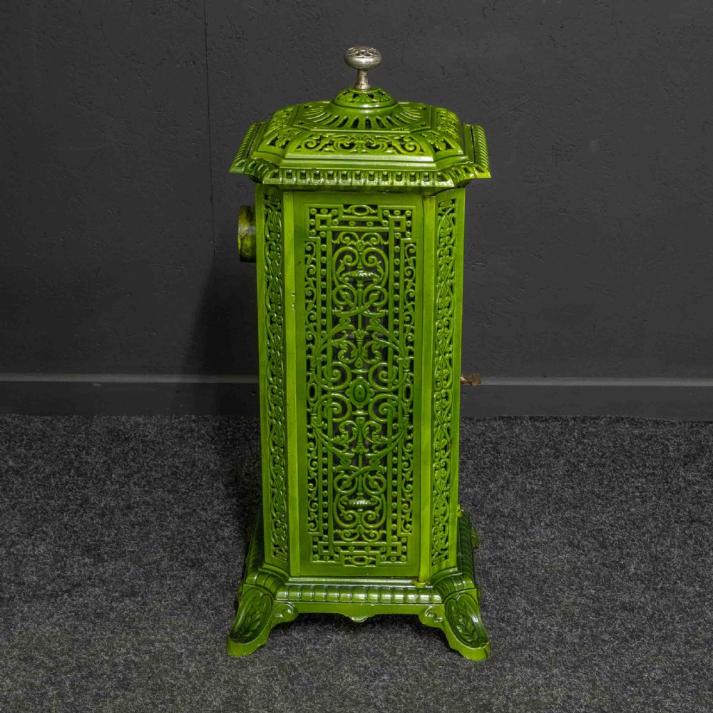 A tall rectangular green enamelled cast iron stove with elaborate openwork pierced filigree patterning and scrolled feet. View XII
