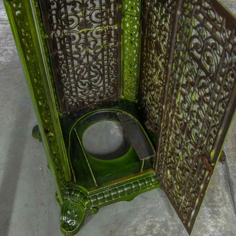 A tall rectangular green enamelled cast iron stove with elaborate openwork pierced filigree patterning and scrolled feet. View XVI