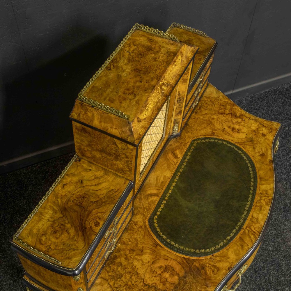 A Victorian burr walnut bonheur de jour featuring floral marquetry inlays, gilt brass mounts, cabriole legs, and a green leather writing surface. View II
