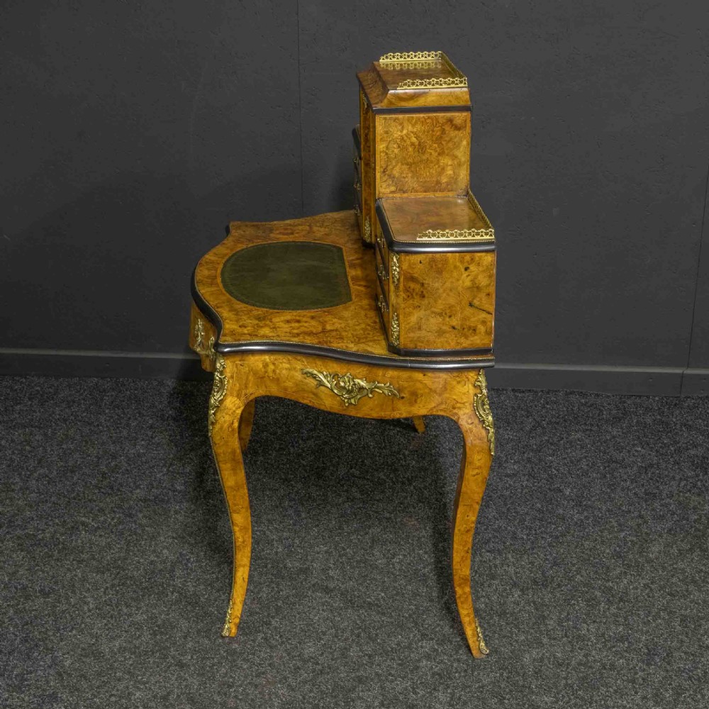 A Victorian burr walnut bonheur de jour featuring floral marquetry inlays, gilt brass mounts, cabriole legs, and a green leather writing surface. View VII