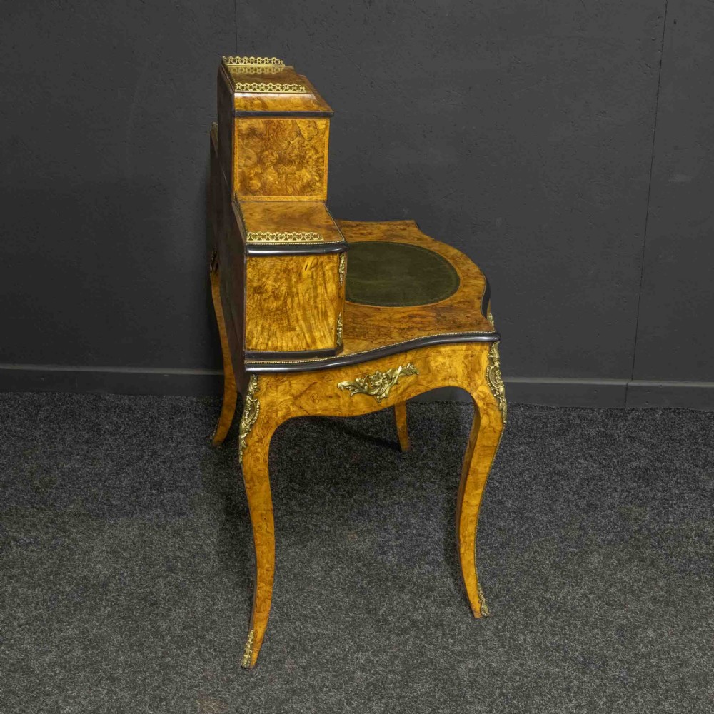 A Victorian burr walnut bonheur de jour featuring floral marquetry inlays, gilt brass mounts, cabriole legs, and a green leather writing surface. View IX