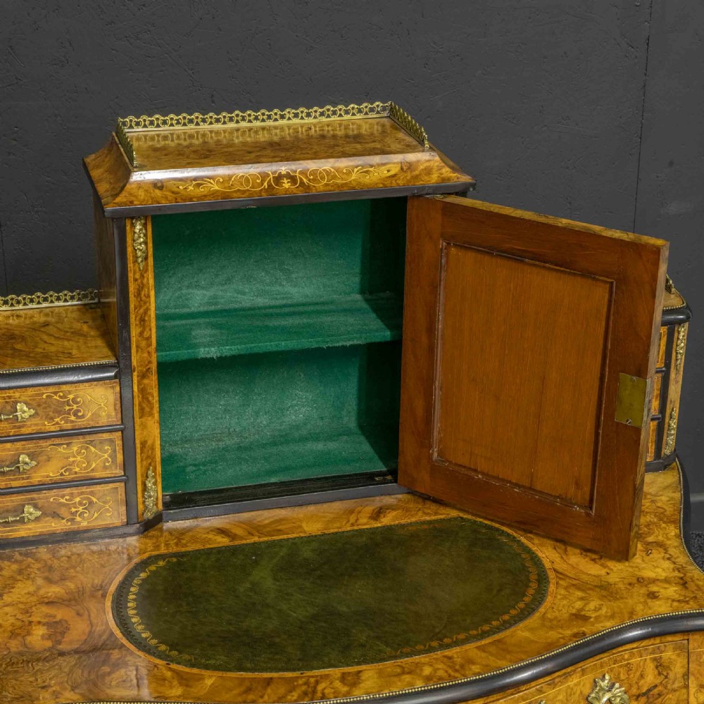 A Victorian burr walnut bonheur de jour featuring floral marquetry inlays, gilt brass mounts, cabriole legs, and a green leather writing surface. View XI