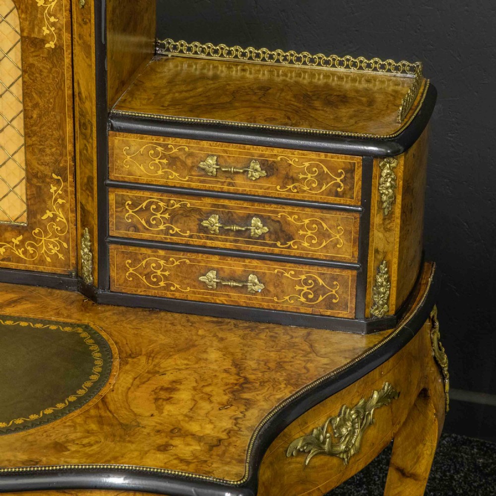 A Victorian burr walnut bonheur de jour featuring floral marquetry inlays, gilt brass mounts, cabriole legs, and a green leather writing surface. View XIII