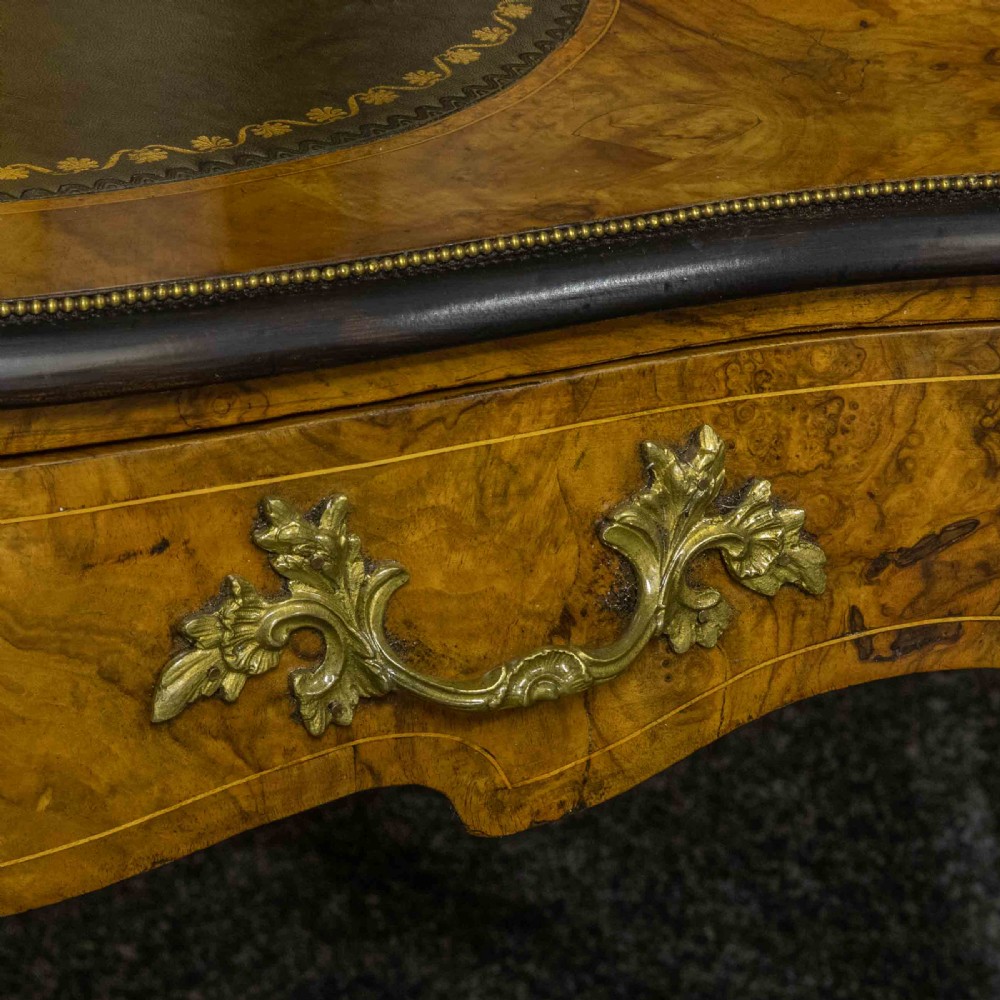 A Victorian burr walnut bonheur de jour featuring floral marquetry inlays, gilt brass mounts, cabriole legs, and a green leather writing surface. View XVI