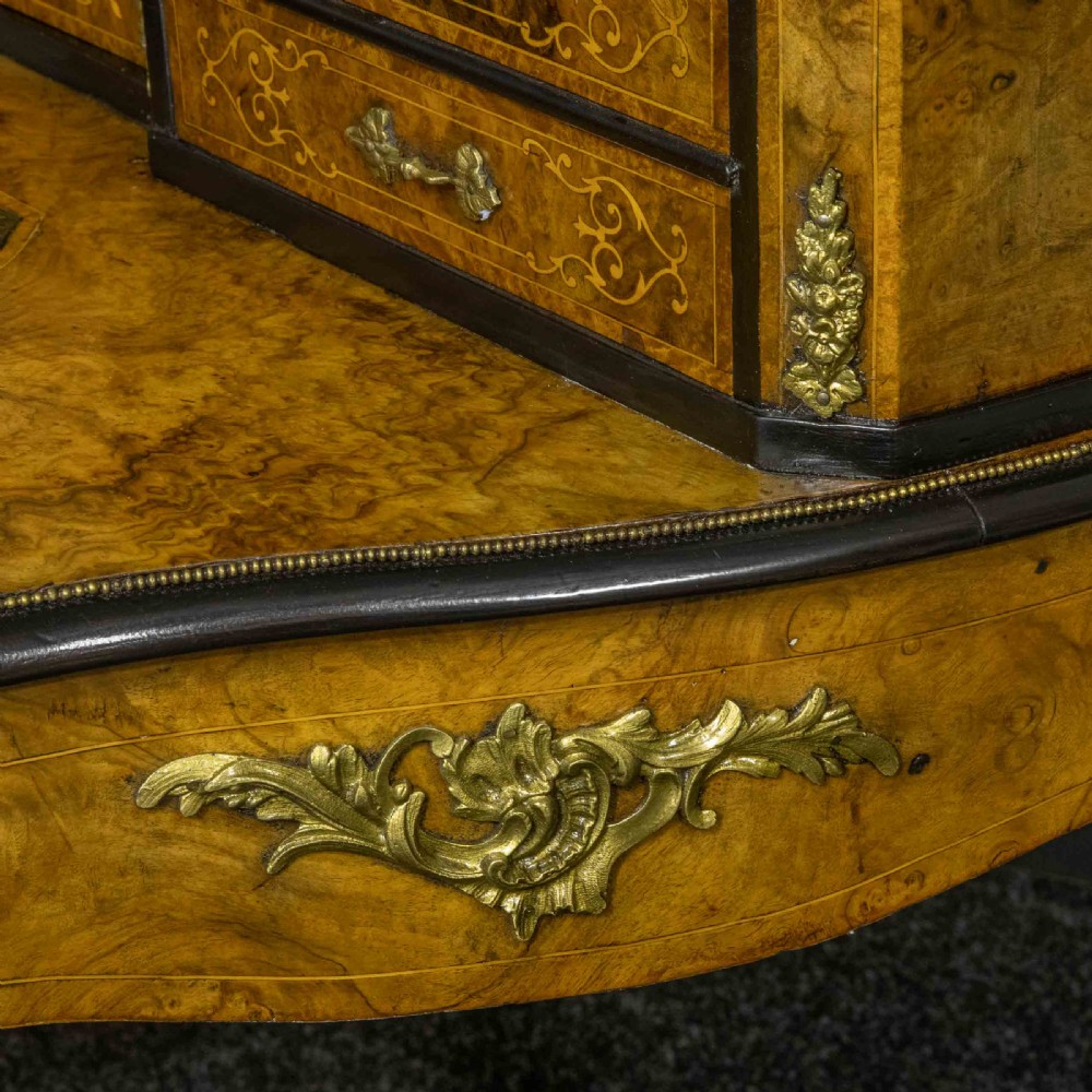 A Victorian burr walnut bonheur de jour featuring floral marquetry inlays, gilt brass mounts, cabriole legs, and a green leather writing surface. View XVIII