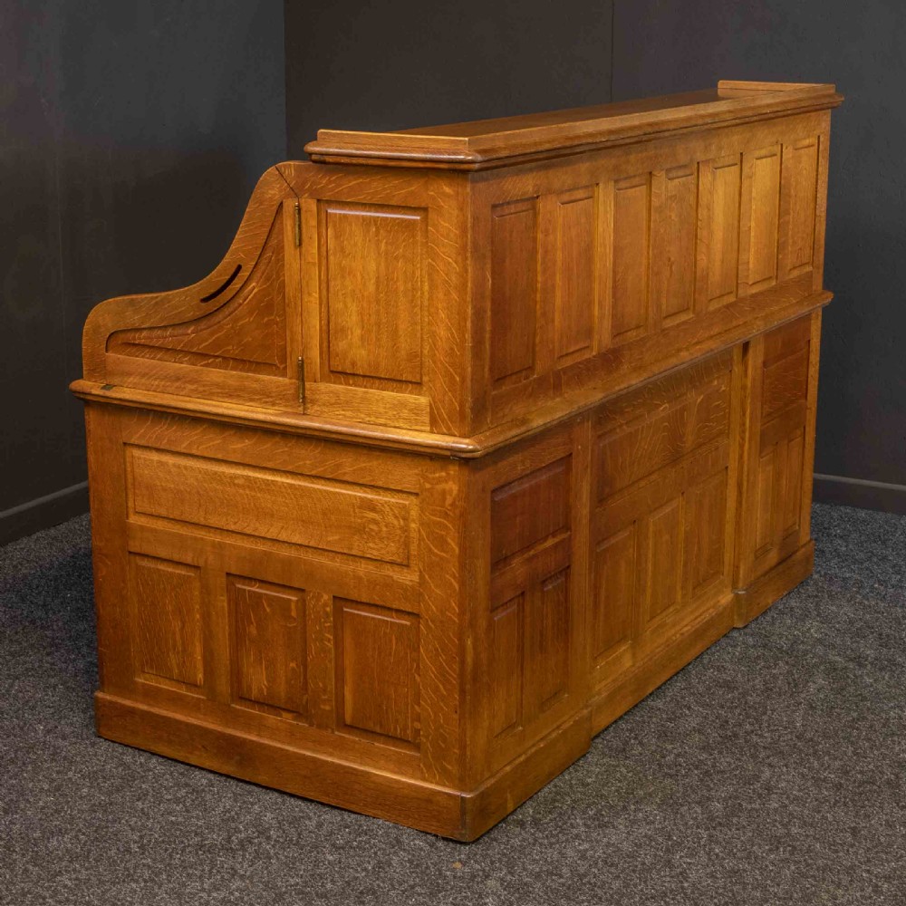 A large Edwardian golden oak roll-top desk featuring a slatted tambour cover, an extensive fitted interior with small drawers and pigeonholes, and twin pedestals with carved wooden handles. View VII