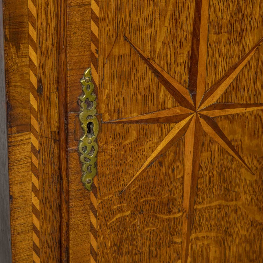 A tall Georgian carved oak longcase clock featuring an arched fretwork pediment, a brass square dial with Roman numerals, star inlay detailing on the trunk door, and a plinth base. View II