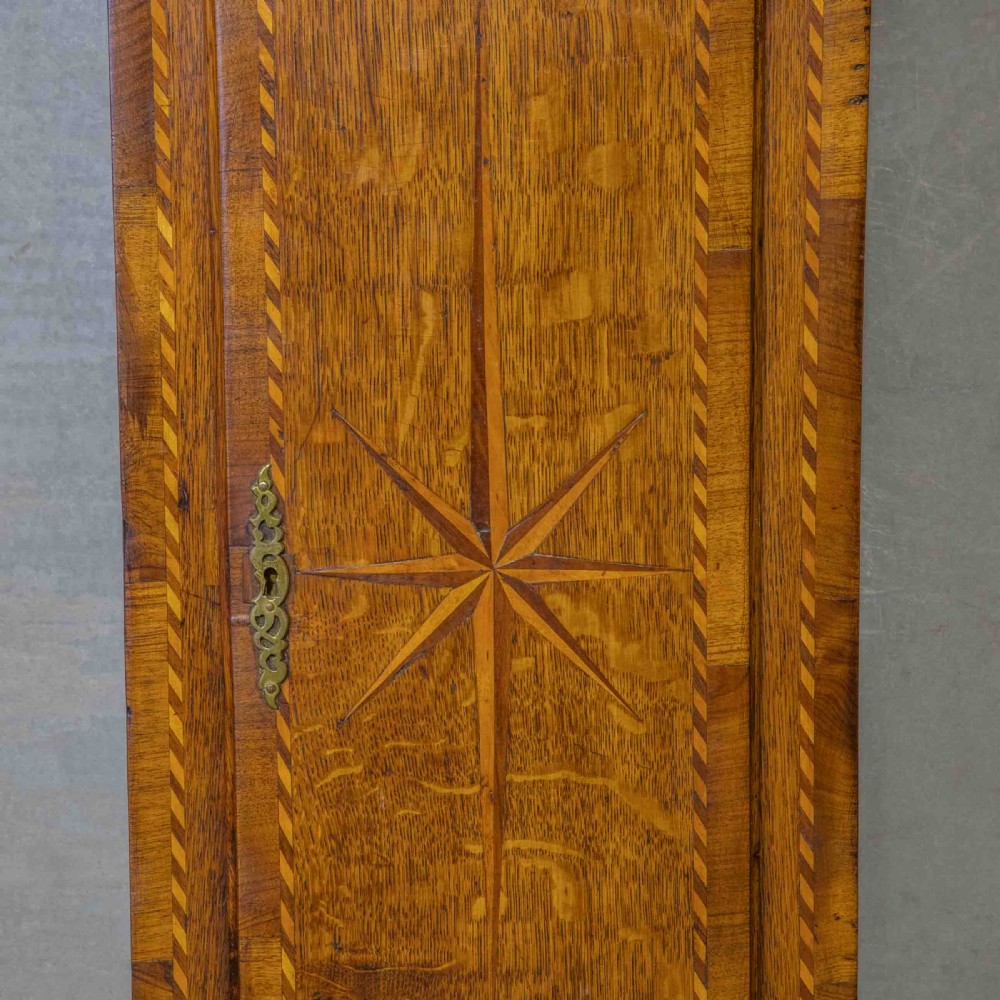 A tall Georgian carved oak longcase clock featuring an arched fretwork pediment, a brass square dial with Roman numerals, star inlay detailing on the trunk door, and a plinth base. View IV