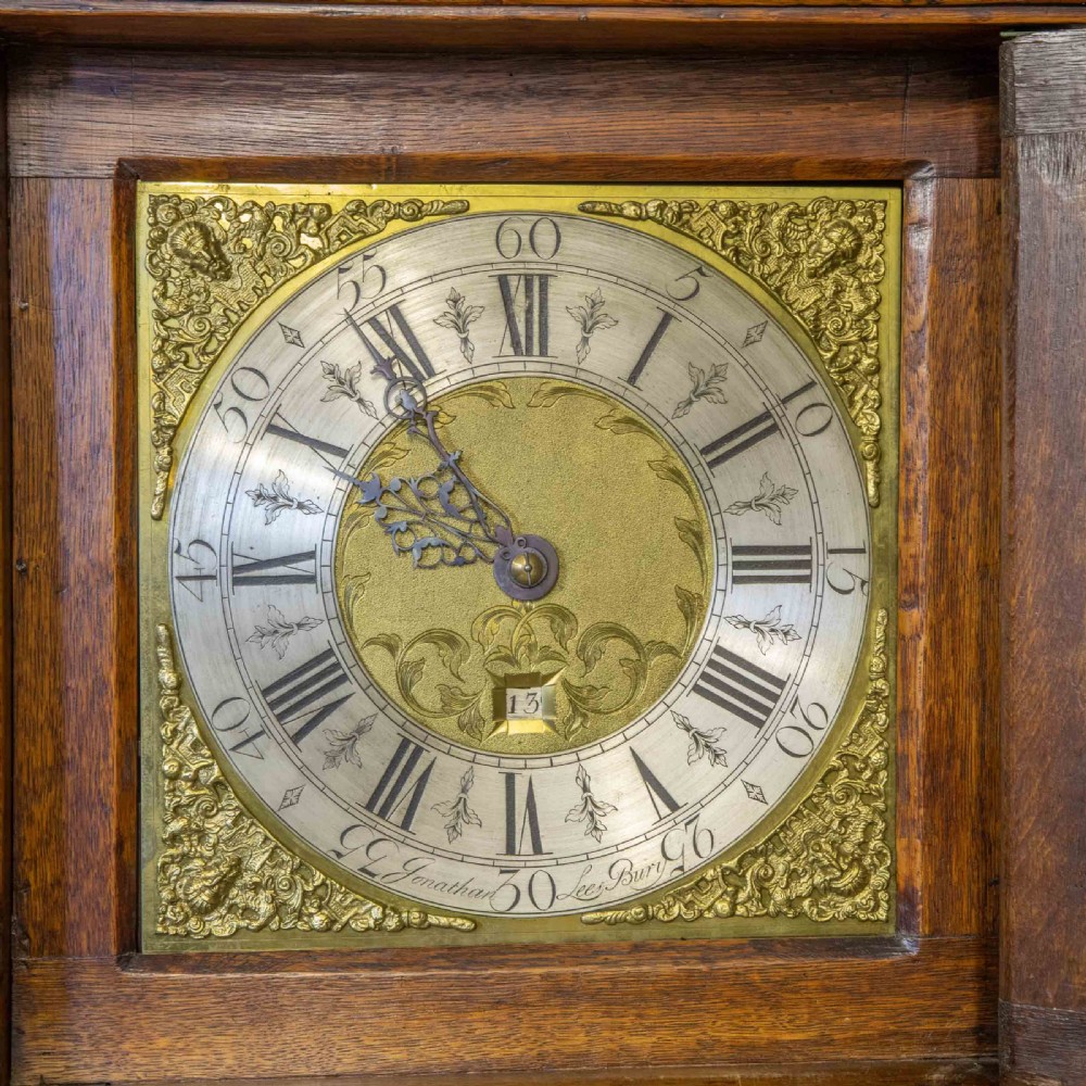 A tall Georgian carved oak longcase clock featuring an arched fretwork pediment, a brass square dial with Roman numerals, star inlay detailing on the trunk door, and a plinth base. View VIII