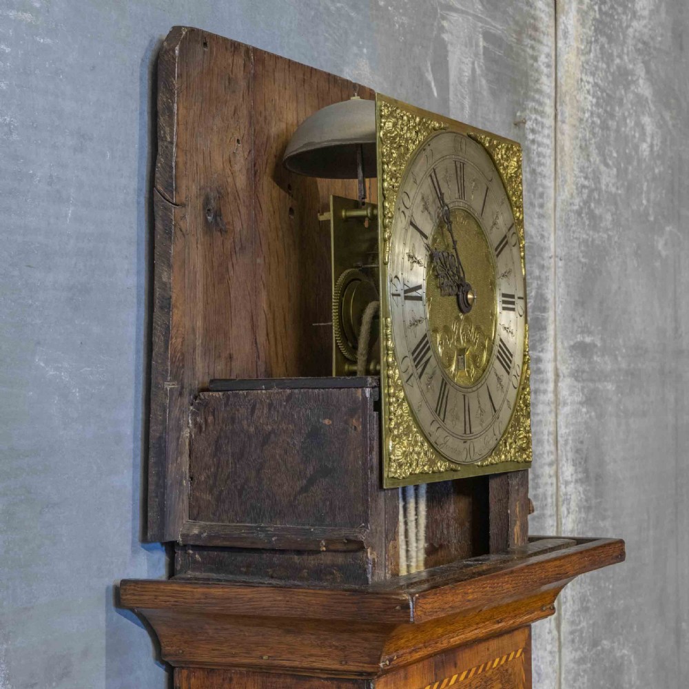 A tall Georgian carved oak longcase clock featuring an arched fretwork pediment, a brass square dial with Roman numerals, star inlay detailing on the trunk door, and a plinth base. View XI