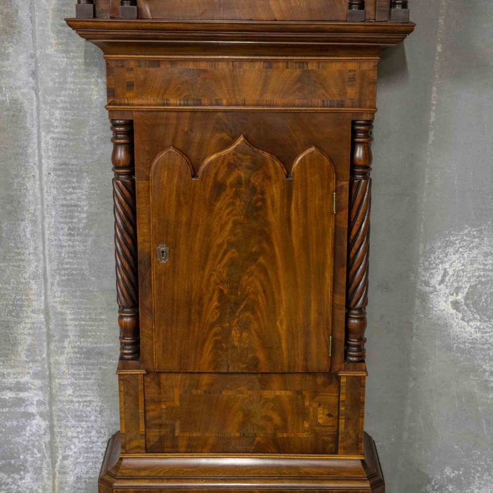 A Georgian mahogany longcase clock featuring a swan-neck pediment with a brass finial, spiral quarter columns, and a hand-painted arch dial. View II