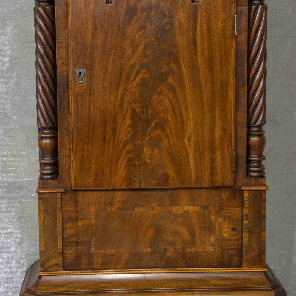 A Georgian mahogany longcase clock featuring a swan-neck pediment with a brass finial, spiral quarter columns, and a hand-painted arch dial. View IV