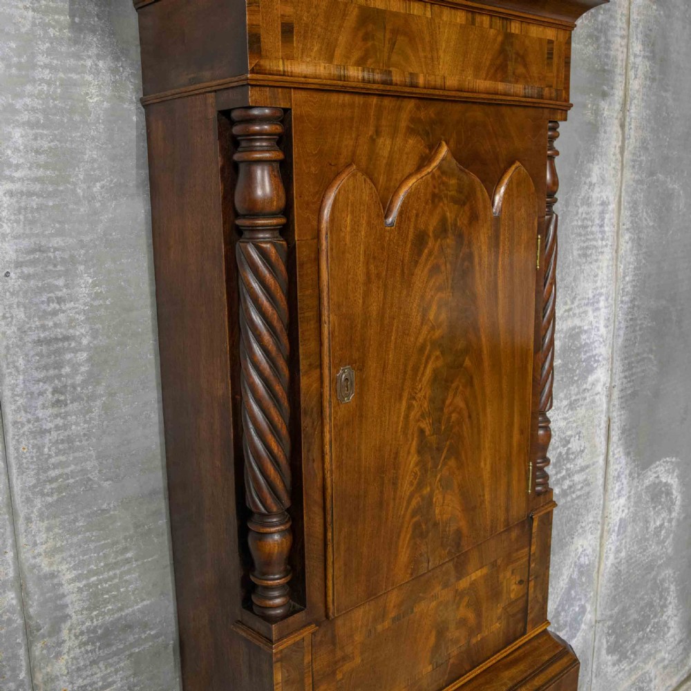 A Georgian mahogany longcase clock featuring a swan-neck pediment with a brass finial, spiral quarter columns, and a hand-painted arch dial. View VI