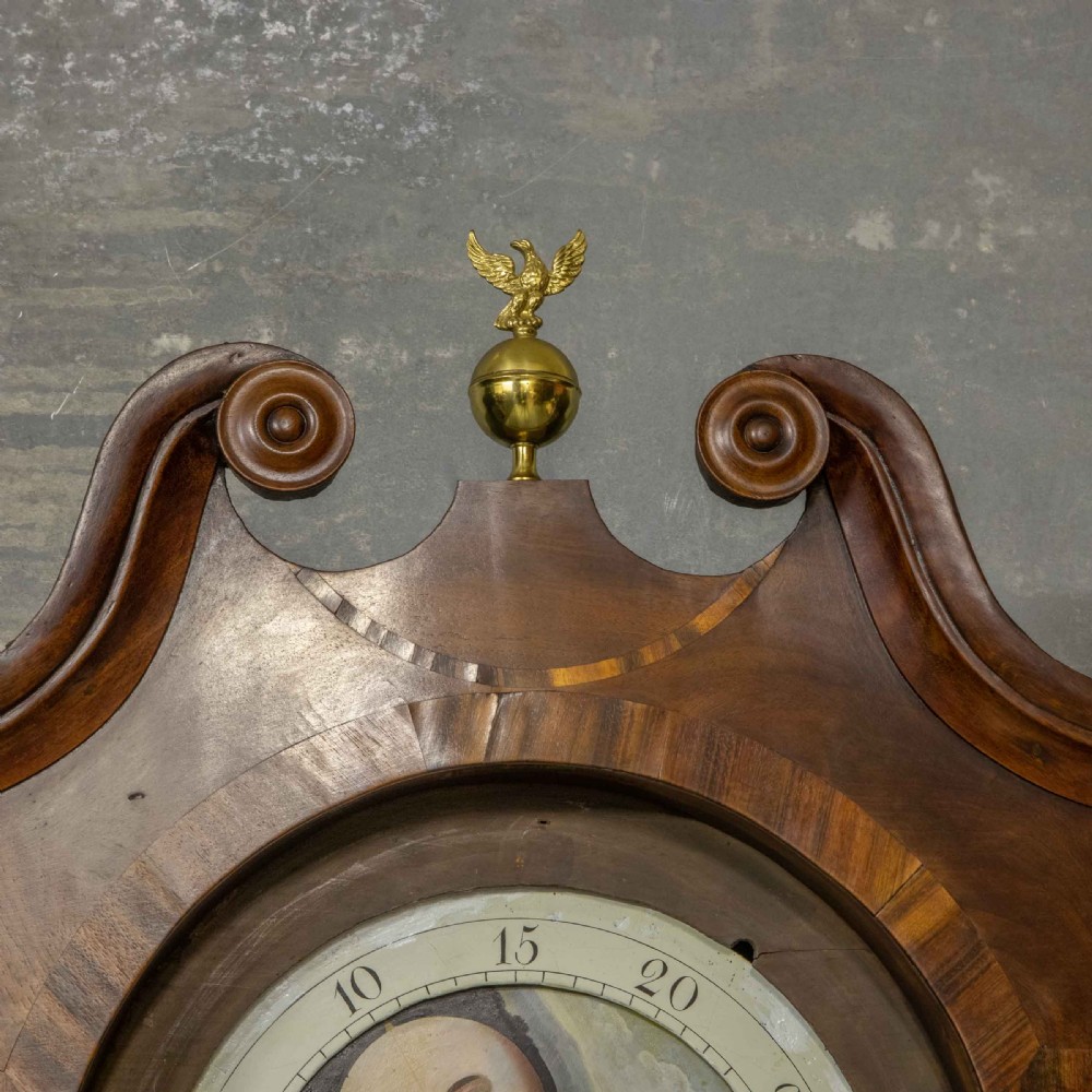 A Georgian mahogany longcase clock featuring a swan-neck pediment with a brass finial, spiral quarter columns, and a hand-painted arch dial. View X