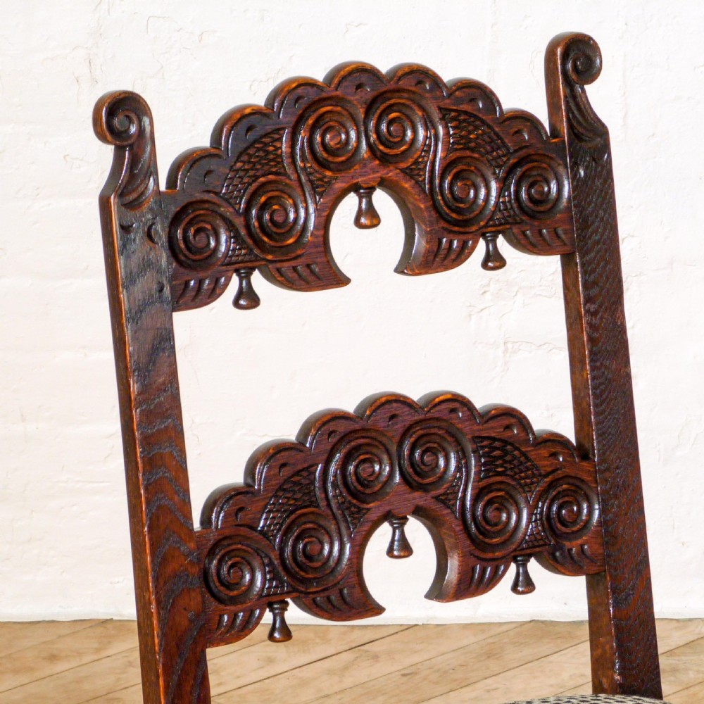 A set of six dark oak Derbyshire style dining chairs featuring intricately carved crescent backs, bobbin-turned front stretchers, and patterned upholstered seats. View III
