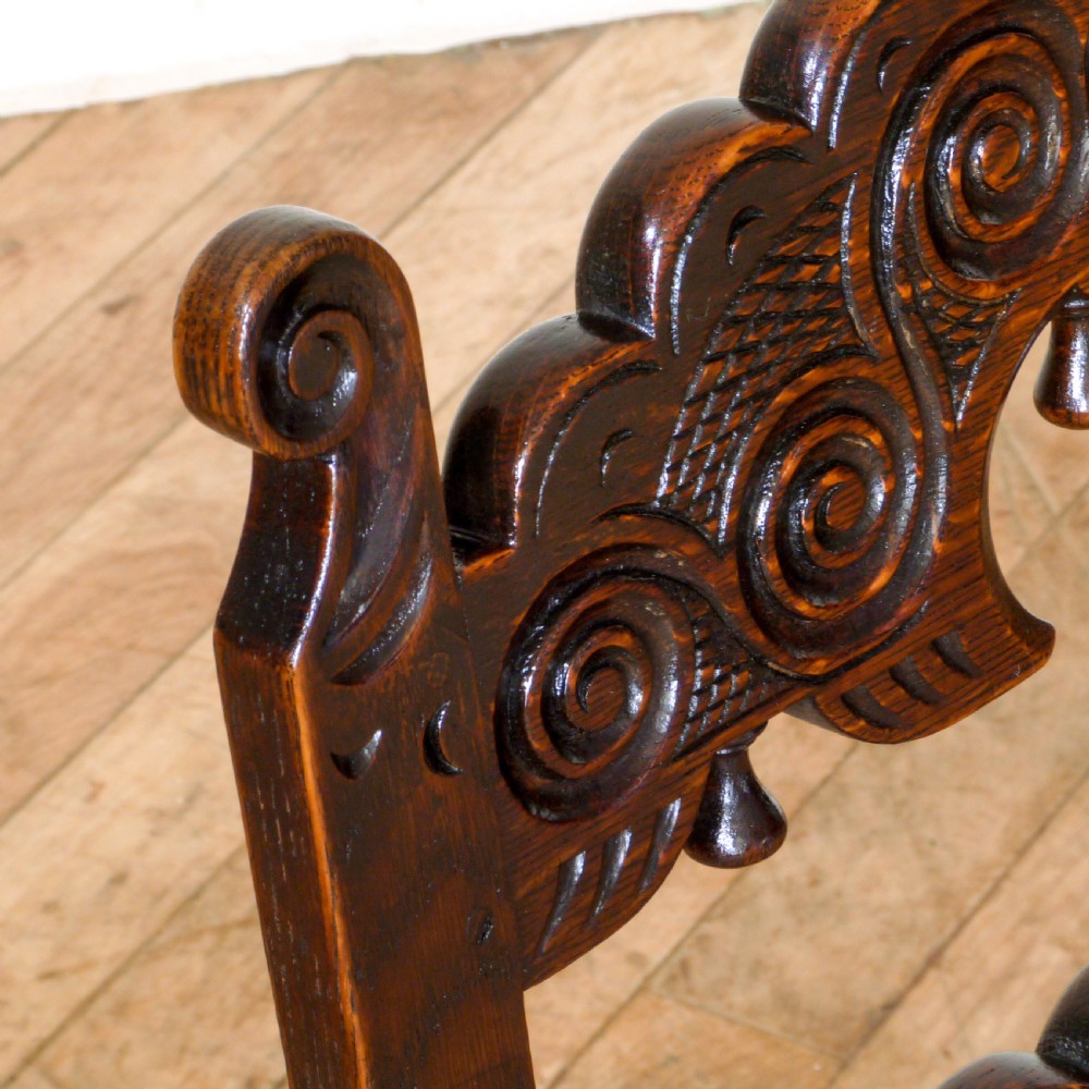 A set of six dark oak Derbyshire style dining chairs featuring intricately carved crescent backs, bobbin-turned front stretchers, and patterned upholstered seats. View V