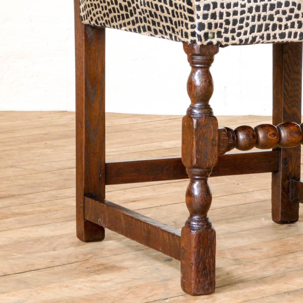 A set of six dark oak Derbyshire style dining chairs featuring intricately carved crescent backs, bobbin-turned front stretchers, and patterned upholstered seats. View VI