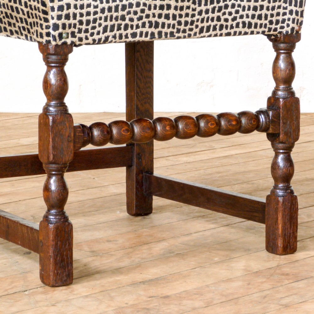 A set of six dark oak Derbyshire style dining chairs featuring intricately carved crescent backs, bobbin-turned front stretchers, and patterned upholstered seats. View X
