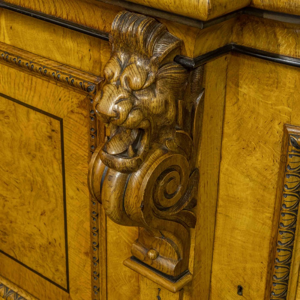 A Victorian pollard oak credenza featuring curved breakfront ends, ebonised geometric line inlay, and carved lion mask corbels. View III