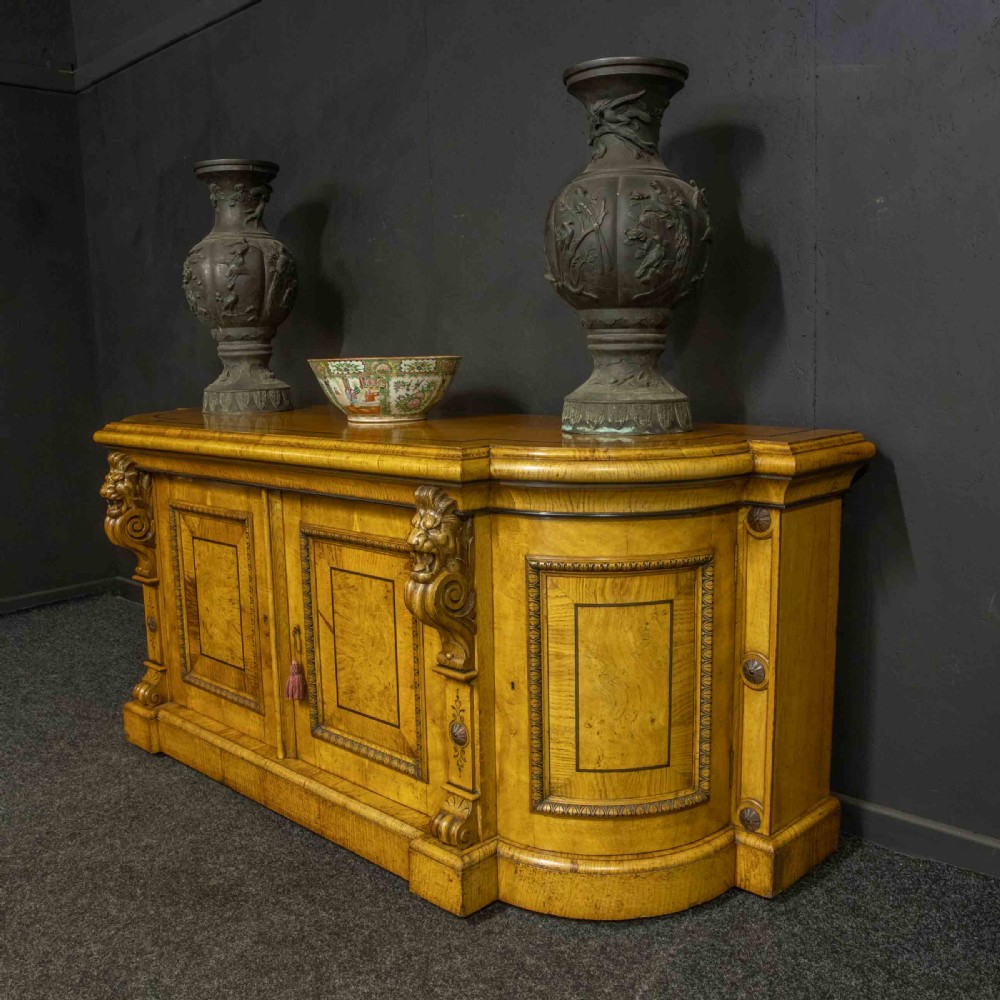 A Victorian pollard oak credenza featuring curved breakfront ends, ebonised geometric line inlay, and carved lion mask corbels. View IV
