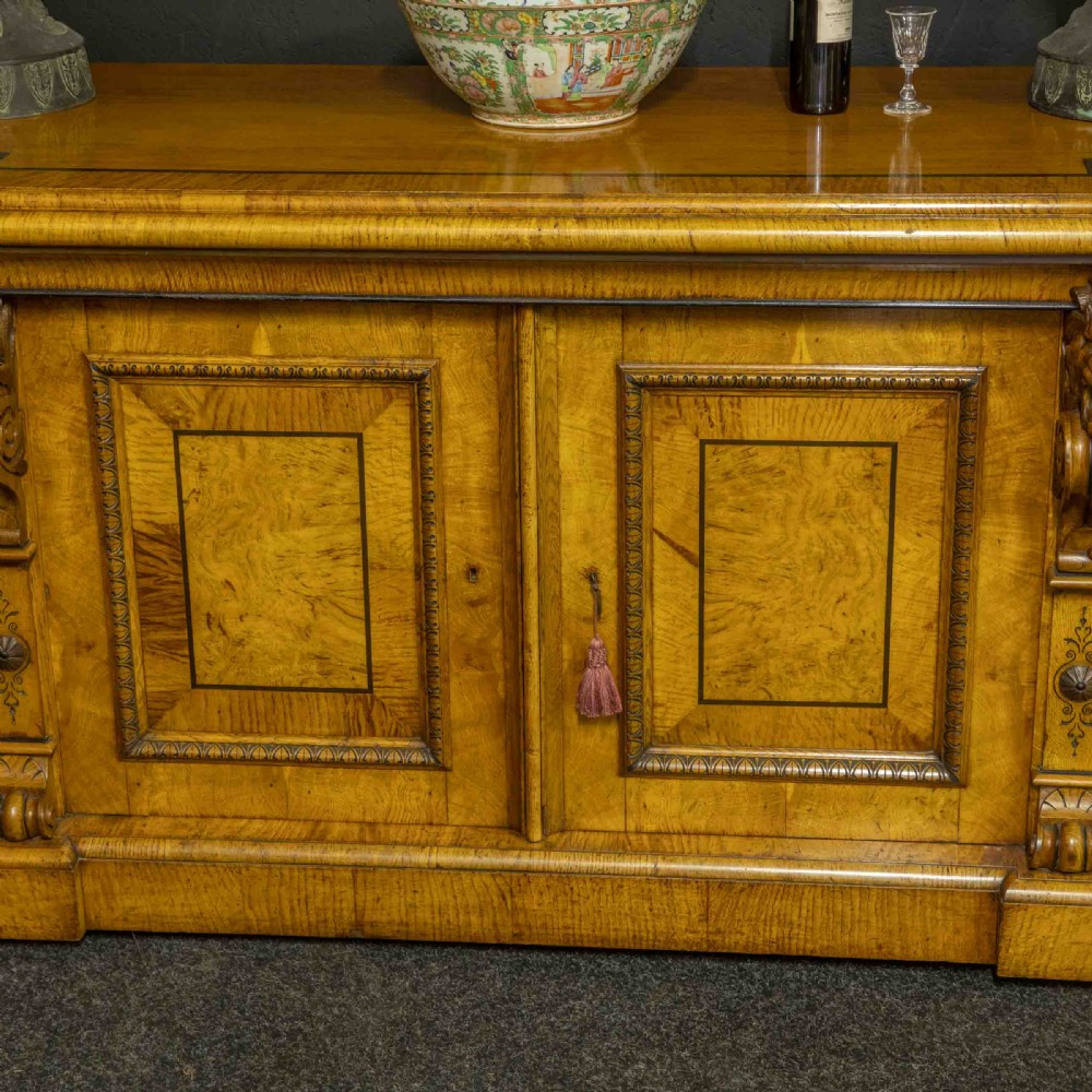 A Victorian pollard oak credenza featuring curved breakfront ends, ebonised geometric line inlay, and carved lion mask corbels. View V