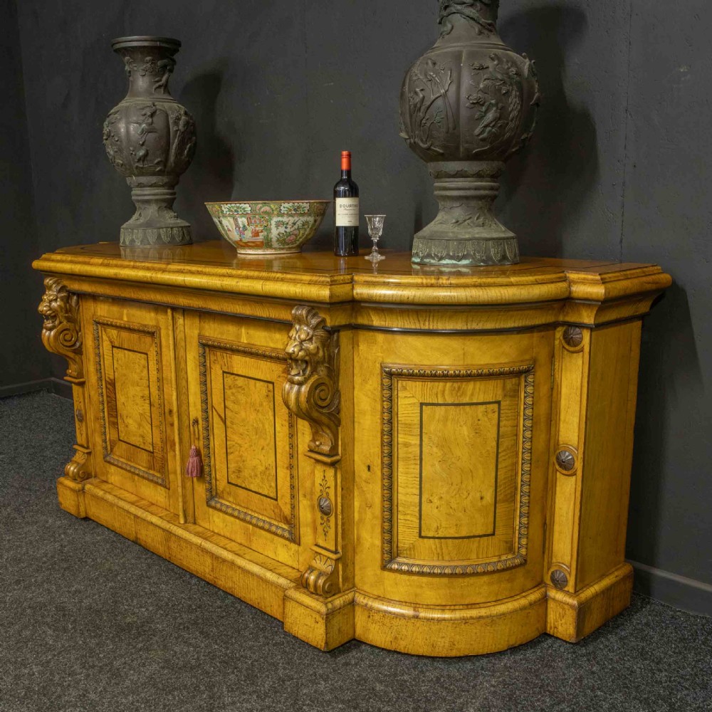 A Victorian pollard oak credenza featuring curved breakfront ends, ebonised geometric line inlay, and carved lion mask corbels. View VI