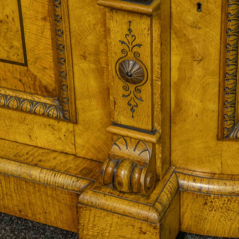 A Victorian pollard oak credenza featuring curved breakfront ends, ebonised geometric line inlay, and carved lion mask corbels. View VII