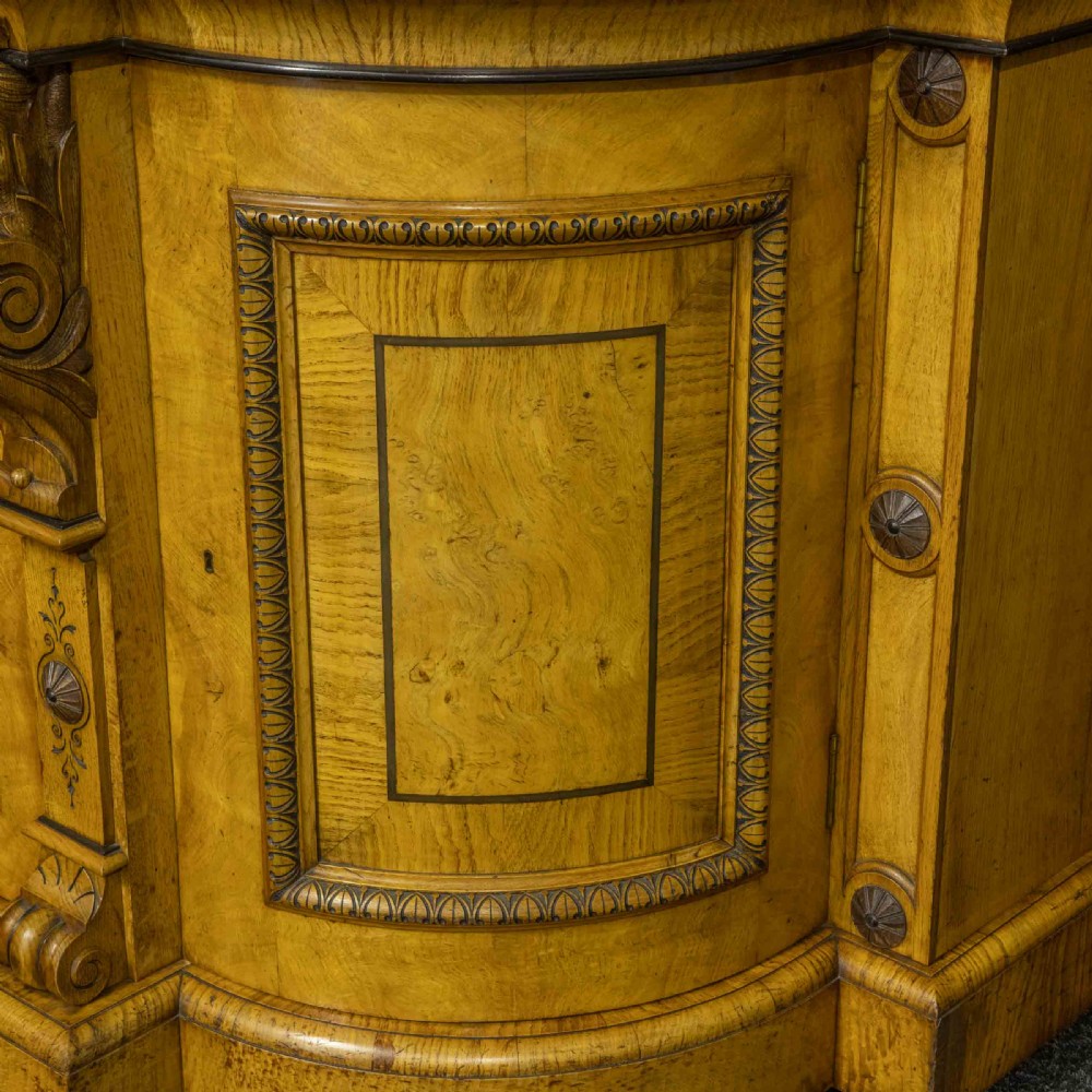 A Victorian pollard oak credenza featuring curved breakfront ends, ebonised geometric line inlay, and carved lion mask corbels. View VIII