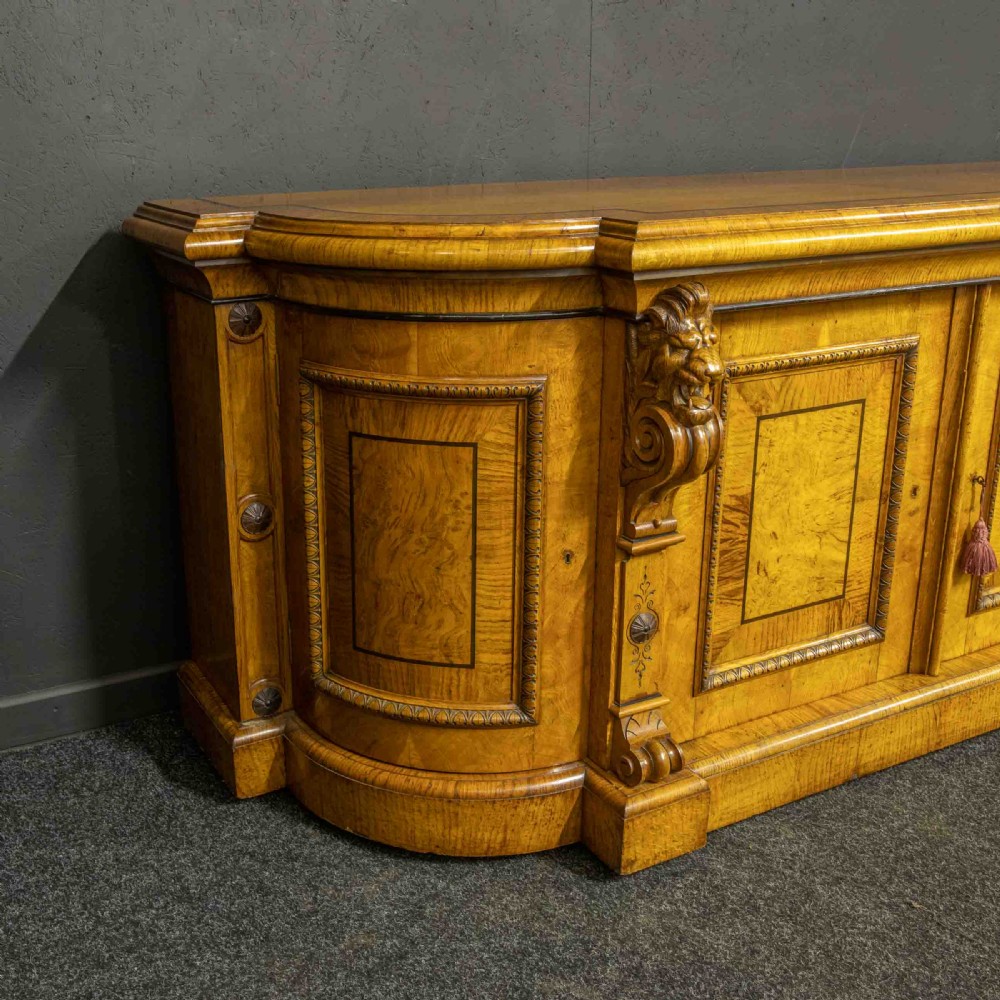 A Victorian pollard oak credenza featuring curved breakfront ends, ebonised geometric line inlay, and carved lion mask corbels. View IX