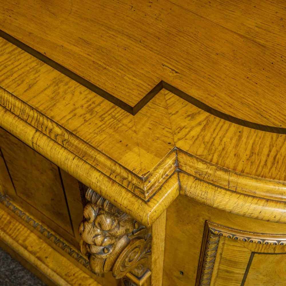 A Victorian pollard oak credenza featuring curved breakfront ends, ebonised geometric line inlay, and carved lion mask corbels. View XI