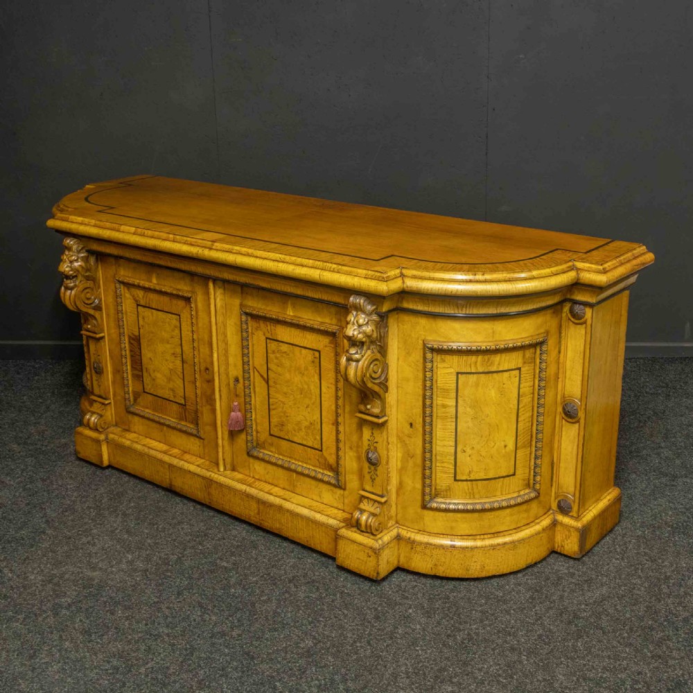 A Victorian pollard oak credenza featuring curved breakfront ends, ebonised geometric line inlay, and carved lion mask corbels. View XII