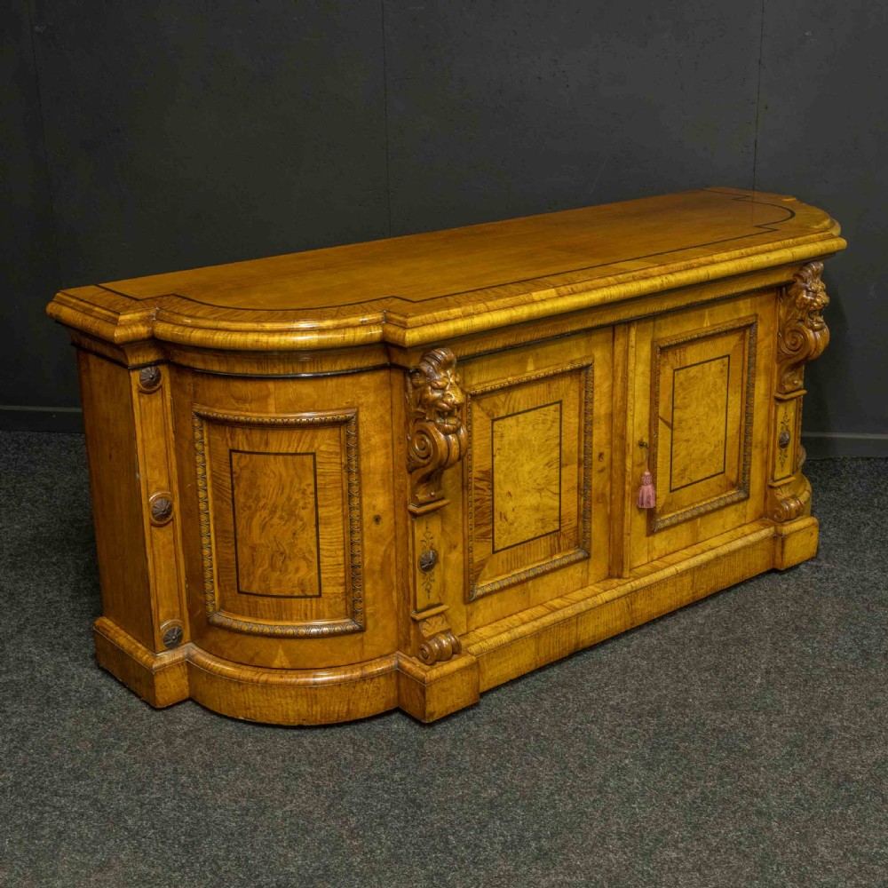 A Victorian pollard oak credenza featuring curved breakfront ends, ebonised geometric line inlay, and carved lion mask corbels. View XIII