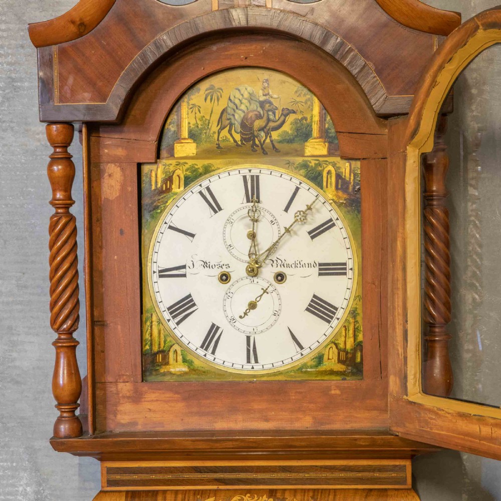 A tall Georgian mahogany longcase clock featuring a swan-neck pediment, turned side columns, floral marquetry inlays, and a painted clock face with Roman numerals. View V