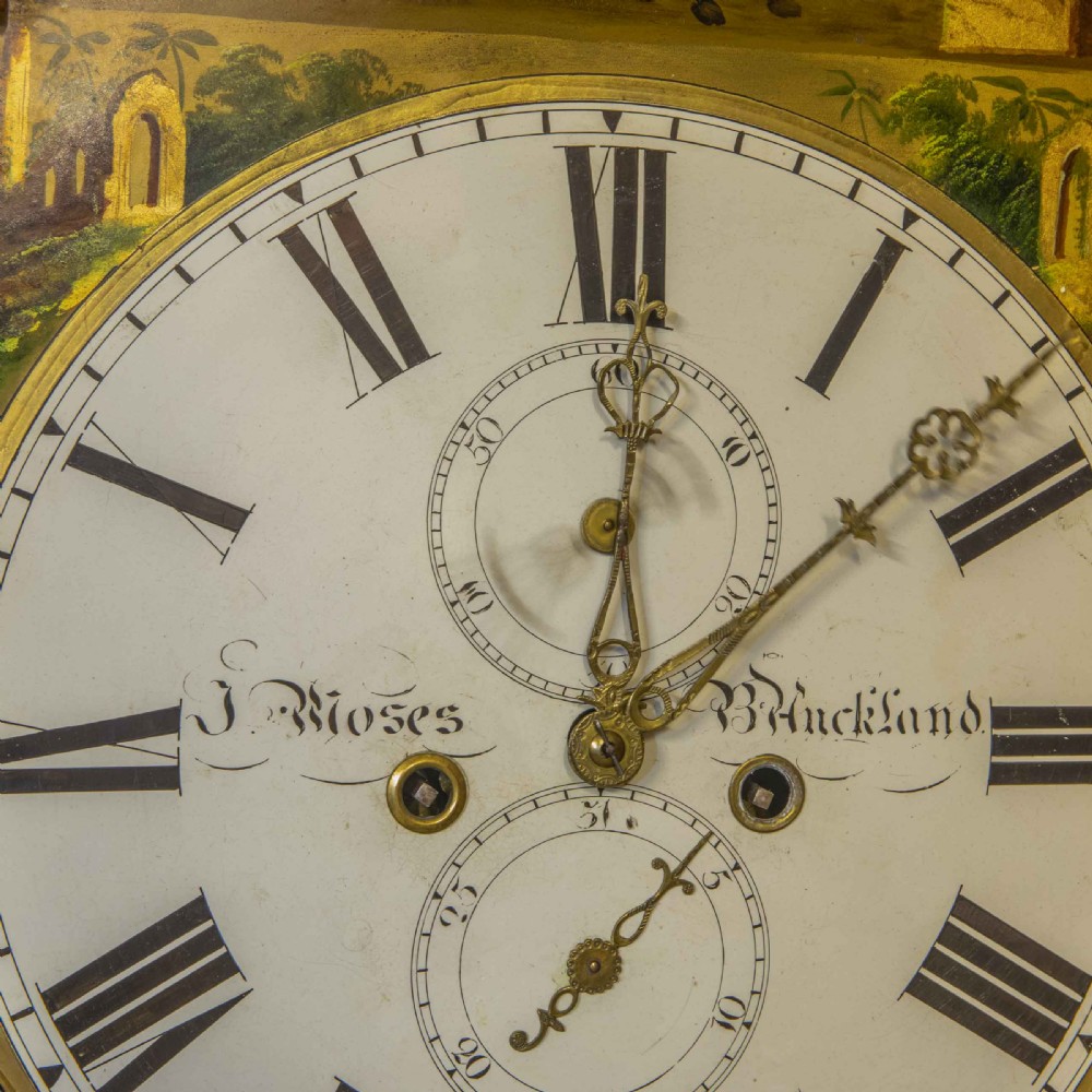 A tall Georgian mahogany longcase clock featuring a swan-neck pediment, turned side columns, floral marquetry inlays, and a painted clock face with Roman numerals. View VIII