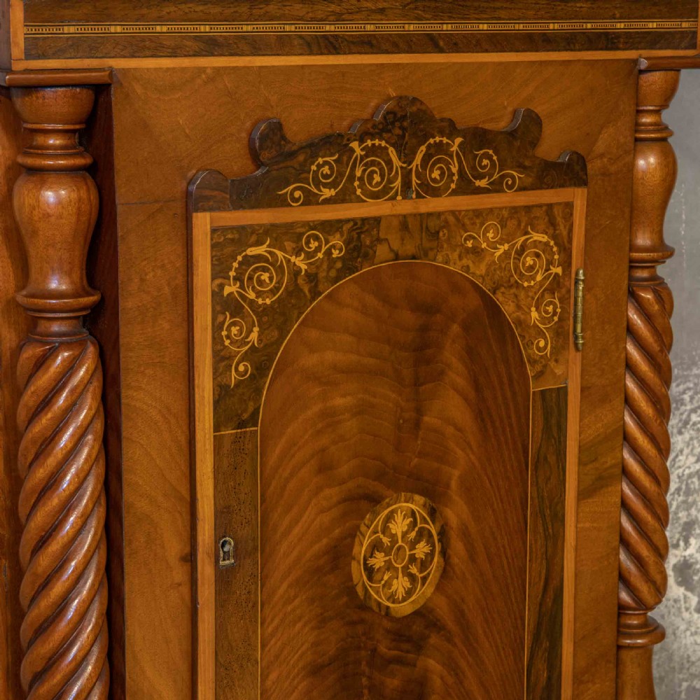 A tall Georgian mahogany longcase clock featuring a swan-neck pediment, turned side columns, floral marquetry inlays, and a painted clock face with Roman numerals. View IX