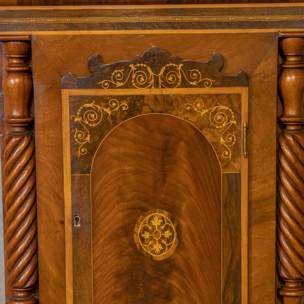 A tall Georgian mahogany longcase clock featuring a swan-neck pediment, turned side columns, floral marquetry inlays, and a painted clock face with Roman numerals. View XI